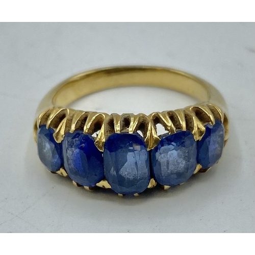 3 - An unmarked yellow metal and sapphire five stone ring, Graduated line of oval free cut sapphires. 9,... 