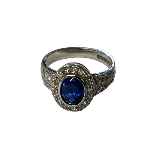 83 - A 18ct white gold sapphire and diamond ring, central oval free cut sapphire in a rub over setting wi... 