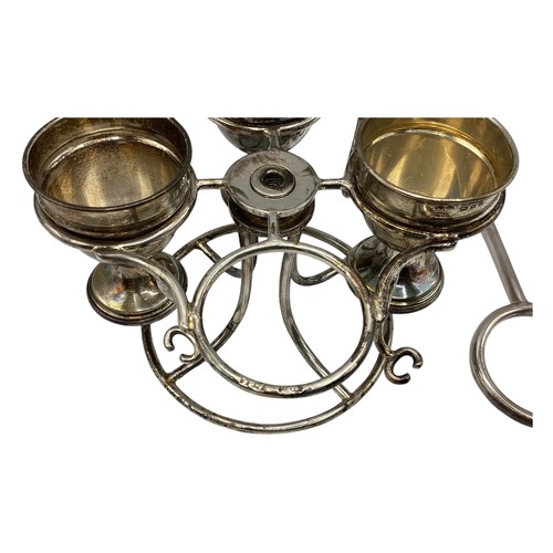 71 - A sterling silver egg cup holder with four egg cups and two spoons(two missing) on a sterling silver... 