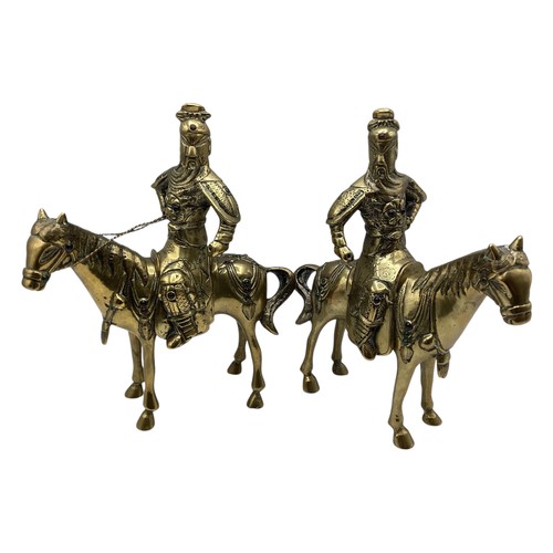 456 - A pair of Oriental brass figures of stylised knights on horseback each set with red and green glass ... 