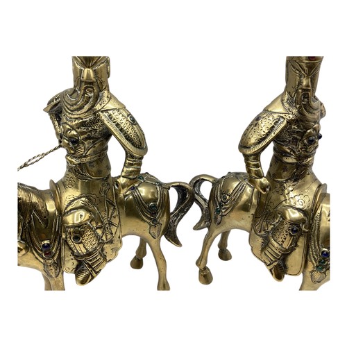 456 - A pair of Oriental brass figures of stylised knights on horseback each set with red and green glass ... 