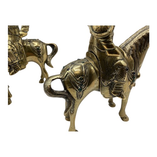 456 - A pair of Oriental brass figures of stylised knights on horseback each set with red and green glass ... 