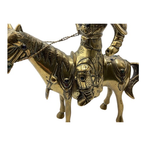 456 - A pair of Oriental brass figures of stylised knights on horseback each set with red and green glass ... 