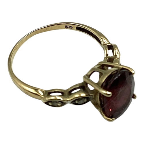 12 - A 9ct gold and Malaya red garnet and diamond ring. Oval free cut garnet in four claw setting with si... 