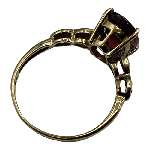 12 - A 9ct gold and Malaya red garnet and diamond ring. Oval free cut garnet in four claw setting with si... 