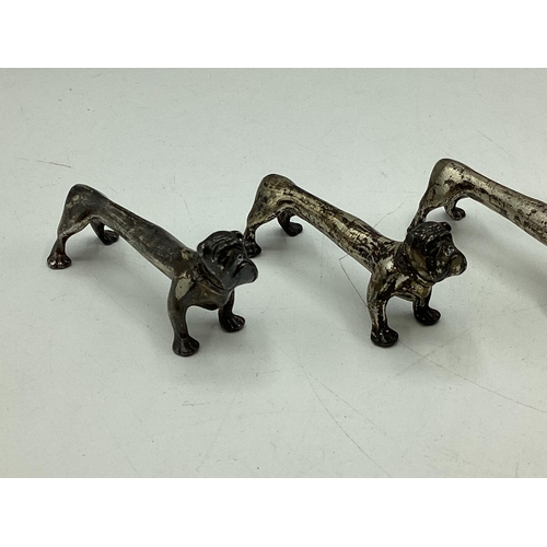 78 - A set of four sterling silver knife rests modelled as stylised hounds. Nat Leslie Ltd, London 1997. ... 