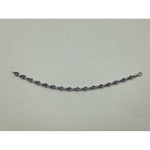 8 - A 9ct white gold and tanzanite set bracelet. Set with sixteen trillion cut tanzanites. Approx 19cm. ... 