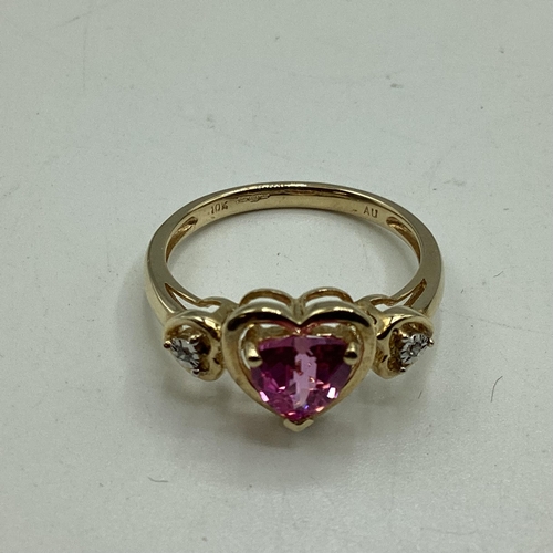 97 - A 10ct gold pink sapphire and diamond ring. Central heart cut sapphire with illusion set single cut ... 