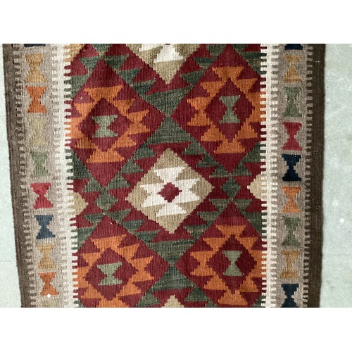 711 - Rug: A Kelim runner  with all over brown and orange central ground and cream, brown , blue and red b... 