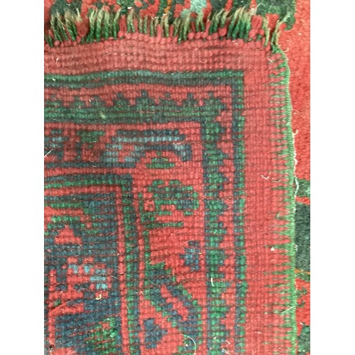 710 - A very large red ground rug with green floral stylized pattern and borders, some all over wear and s... 