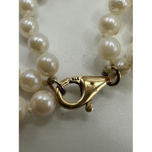 11 - A triple strand of uniform cultured pearls on a 9ct gold clasp. Approx 51cm.