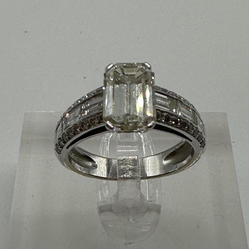 83 - An 18ct white gold and diamond half hoop eternity ring. Central Emerald cut diamond Estimated G/H co... 