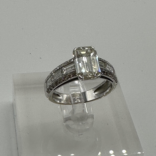 83 - An 18ct white gold and diamond half hoop eternity ring. Central Emerald cut diamond Estimated G/H co... 