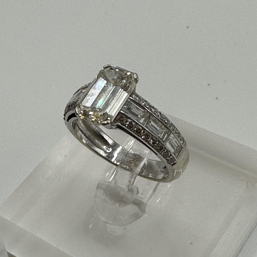 83 - An 18ct white gold and diamond half hoop eternity ring. Central Emerald cut diamond Estimated G/H co... 