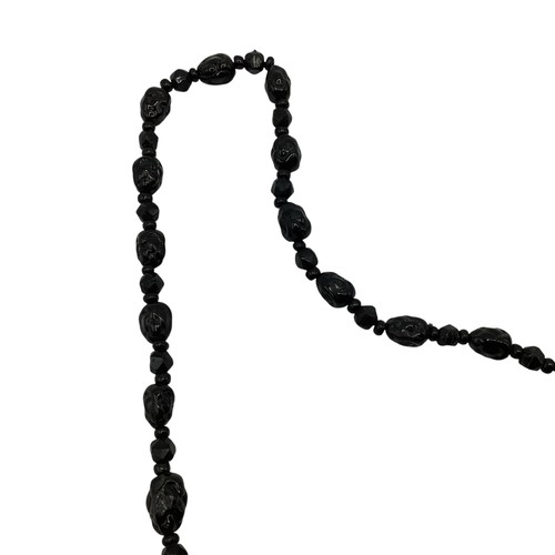 136 - A graduated strand of jet carved beads. 74cm.