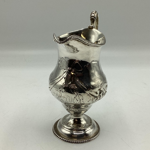 57 - A sterling silver cream jug with repoussé decoration on a beaded circular foot 103 g