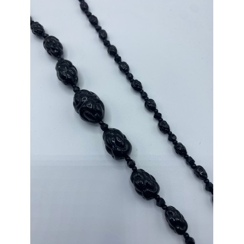 49 - A graduated strand of jet carved beads. 74cm.