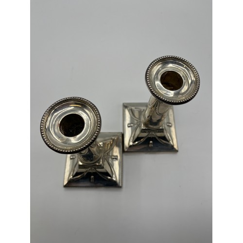 37 - A pair of sterling silver weighted candlesticks, swag and bow design on square bases. Thomas Bradbur... 