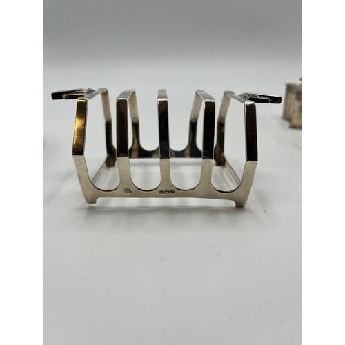 20 - A collection of sterling silver items to include an art Deco style toast rack, tea strainer salts et... 