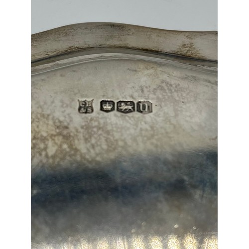 6 - A sterling silver circular card tray raised on three feet. Inscription to front. 21cm(d) 380g