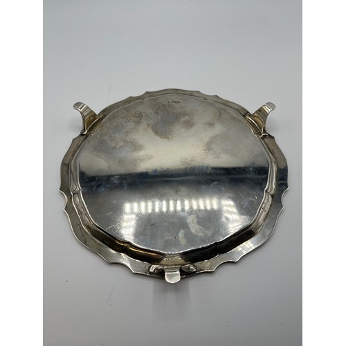 6 - A sterling silver circular card tray raised on three feet. Inscription to front. 21cm(d) 380g