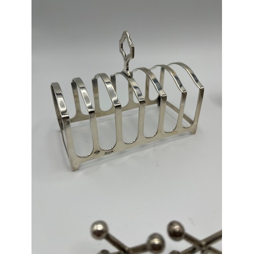 15 - A collection of sterling silver items to include a Georgian sugar sifter, toast rack, pepperettes et... 