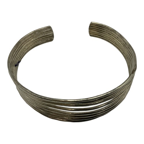 131 - A collection of South Asian unmarked white metal bangles. 117g together with a white metal propellin... 