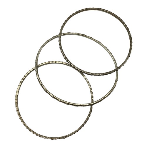 131 - A collection of South Asian unmarked white metal bangles. 117g together with a white metal propellin... 