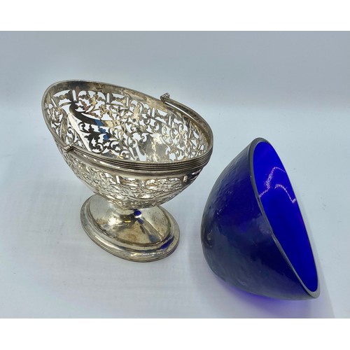 119 - A sterling silver oval swing handle bowl with pierced decoration and blue glass liner by George Nath... 