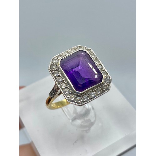 146 - An 18ct yellow and white gold amethyst and diamond dress ring. Emerald cut amethyst with a surround ... 