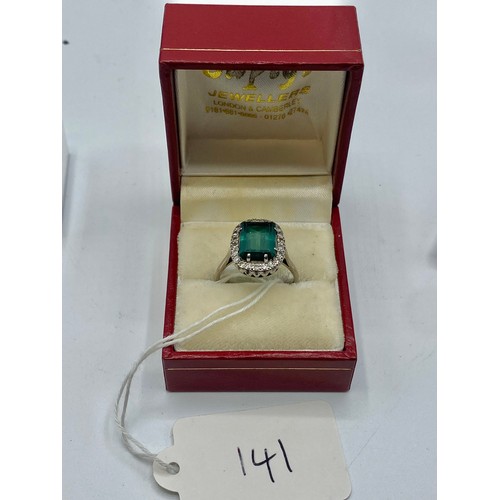 141 - An 18 ct white gold Emerald and Diamond dress ring central step cut Emerald, 13 x 9 mm approx with a... 