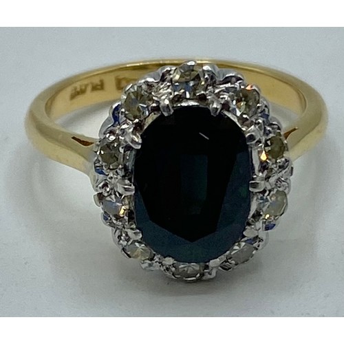 173 - An 18ct gold and platinum sapphire and diamond dress ring. Oval mixed cut sapphire with feint colour... 