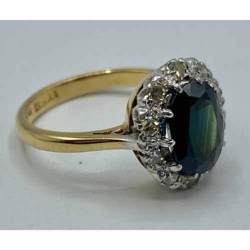 173 - An 18ct gold and platinum sapphire and diamond dress ring. Oval mixed cut sapphire with feint colour... 