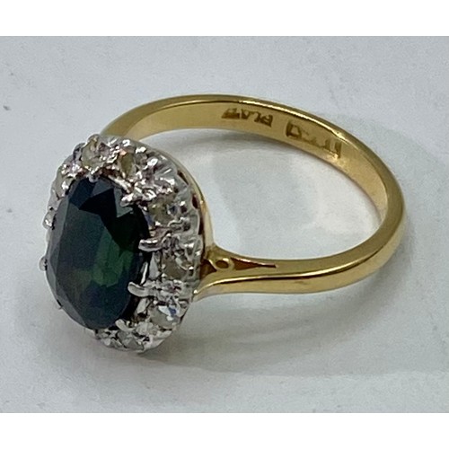 173 - An 18ct gold and platinum sapphire and diamond dress ring. Oval mixed cut sapphire with feint colour... 