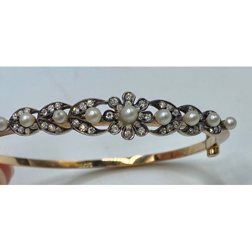 174 - A 15ct gold diamond and pearl set bangle bracelet to a floral and leaf design. 11g.