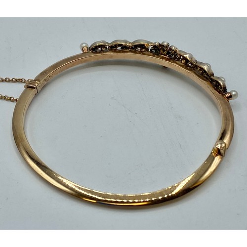 174 - A 15ct gold diamond and pearl set bangle bracelet to a floral and leaf design. 11g.