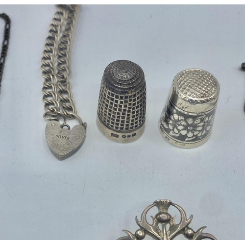 29 - A collection of sterling silver and white metal items to include an enamel brooch, thimbles pendants... 