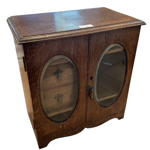 206 - An Oak smokers cabinet with two oval glazed doors. 36cm x 37cm x 21xcm