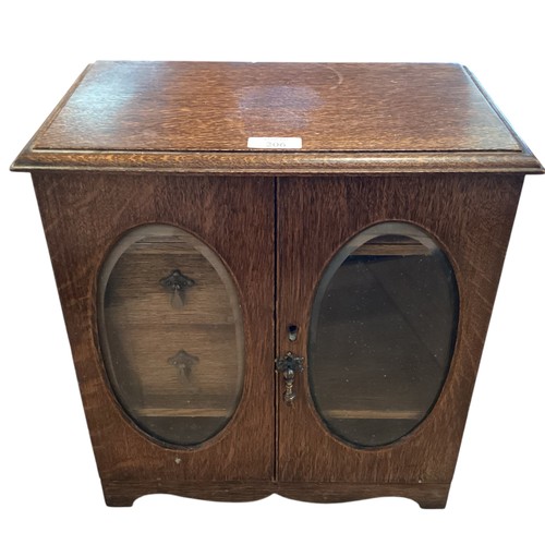 206 - An Oak smokers cabinet with two oval glazed doors. 36cm x 37cm x 21xcm