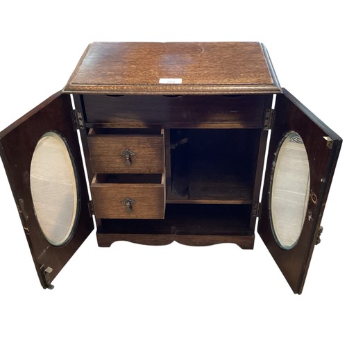 206 - An Oak smokers cabinet with two oval glazed doors. 36cm x 37cm x 21xcm