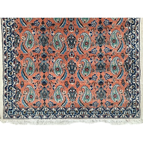 351 - A wool rug with repeat paisley pattern and pattern borders, with salmon orange ground and patterns o... 