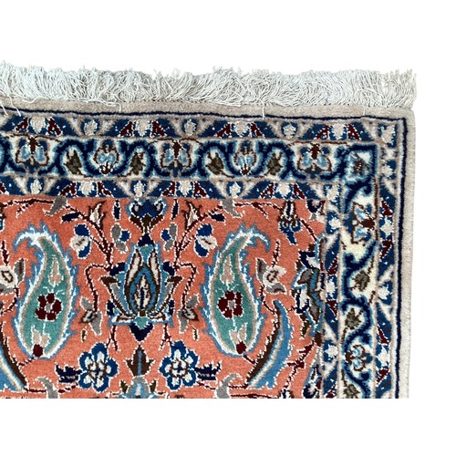 351 - A wool rug with repeat paisley pattern and pattern borders, with salmon orange ground and patterns o... 