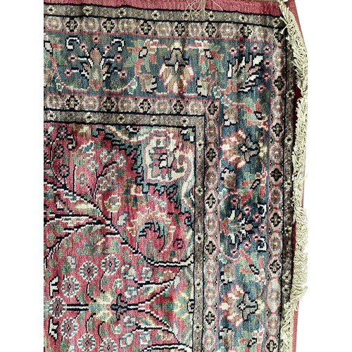 352 - A Kashmir silk rug with pink background and blue and pink border and floral pattern, 94cm x 156cm. G... 