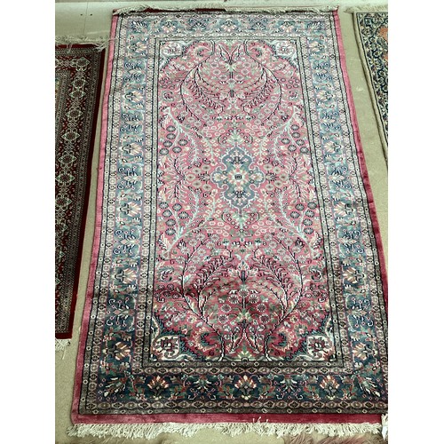 352 - A Kashmir silk rug with pink background and blue and pink border and floral pattern, 94cm x 156cm. G... 