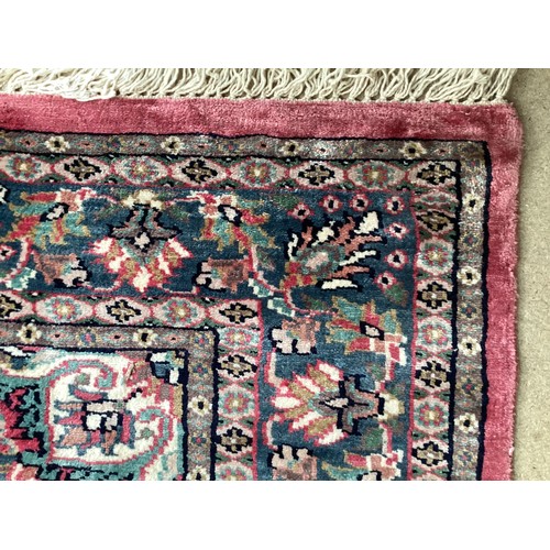 352 - A Kashmir silk rug with pink background and blue and pink border and floral pattern, 94cm x 156cm. G... 