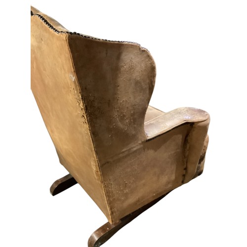 566 - A good, very worn, leather studded wing back rocking (sprung) arm chair, 106 cm H. Condition: much a... 