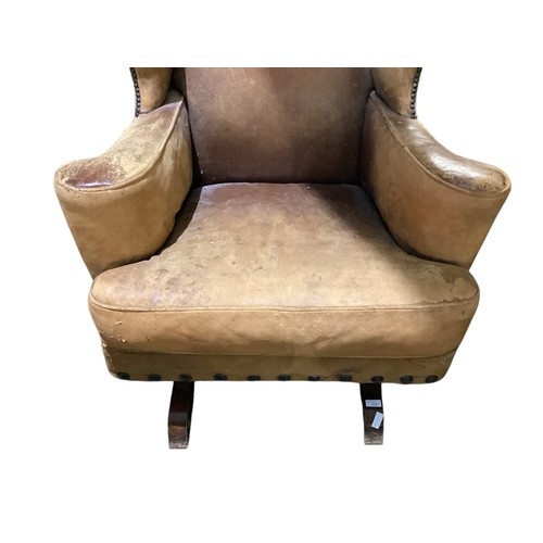 566 - A good, very worn, leather studded wing back rocking (sprung) arm chair, 106 cm H. Condition: much a... 