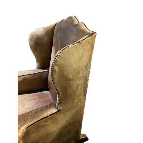 566 - A good, very worn, leather studded wing back rocking (sprung) arm chair, 106 cm H. Condition: much a... 