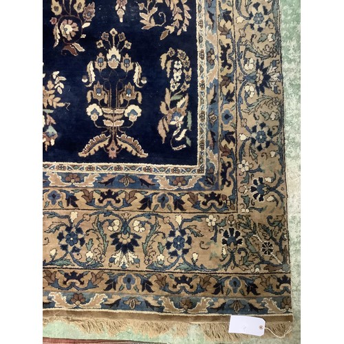 384 - A large Persian style blue ground rug, notable all over wear 255 cm x 404 cm