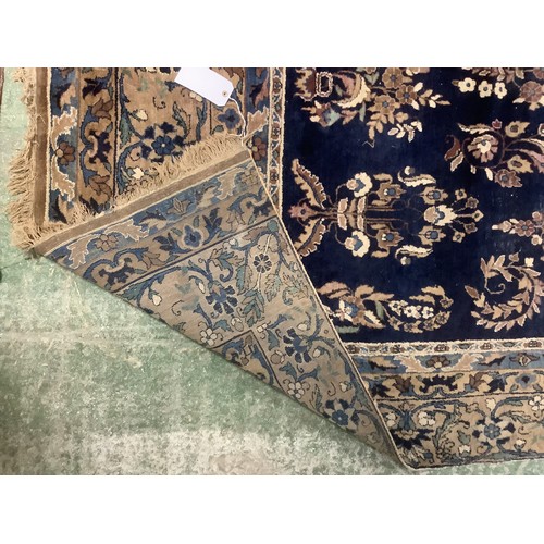 384 - A large Persian style blue ground rug, notable all over wear 255 cm x 404 cm